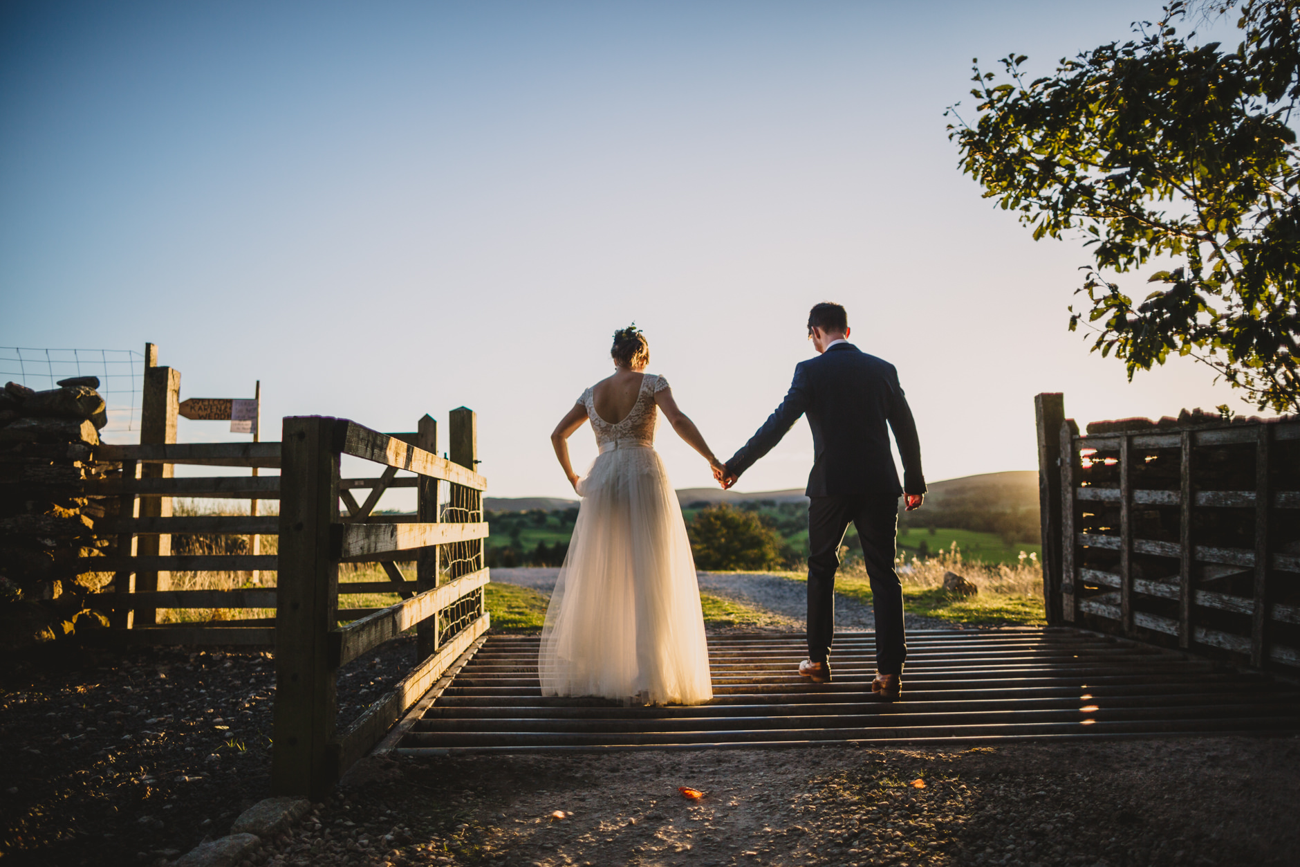 bride and groom crossing cattle grid at knipe hall for sunset portraits