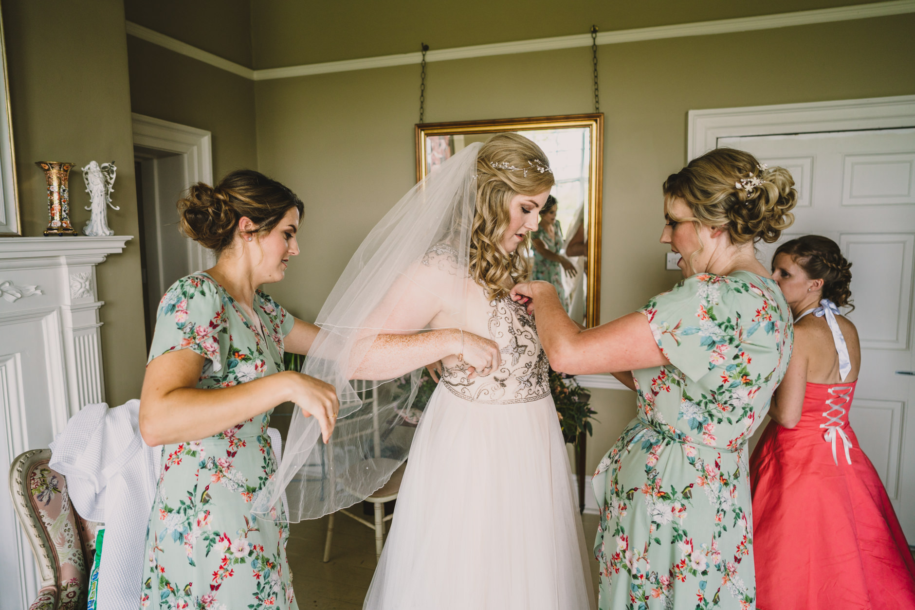 bridesmaids helping bride into her dress in bridal suite at east bridgford hill