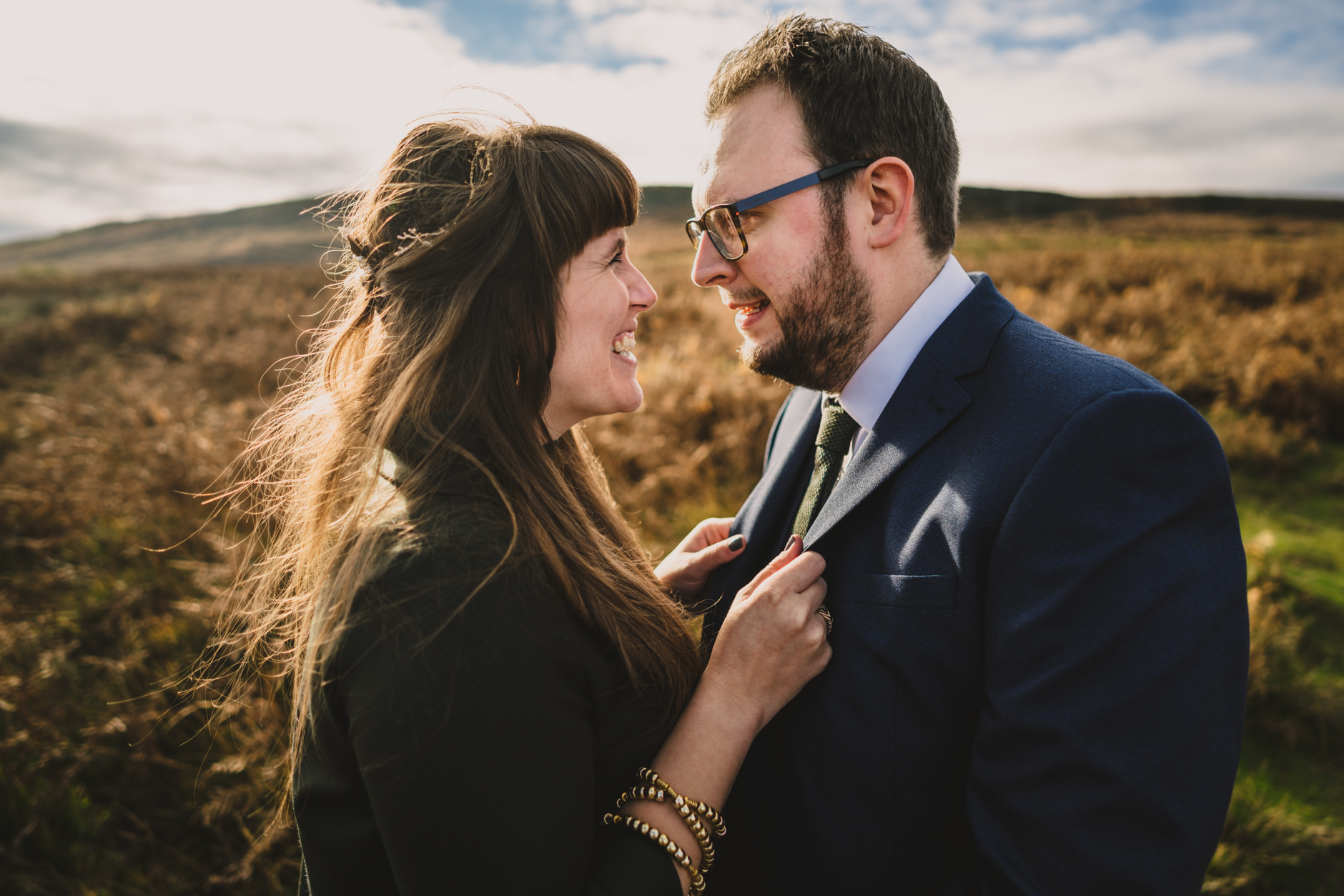 bride in green hold her groom's lapels during couple shoot on ilkley moor