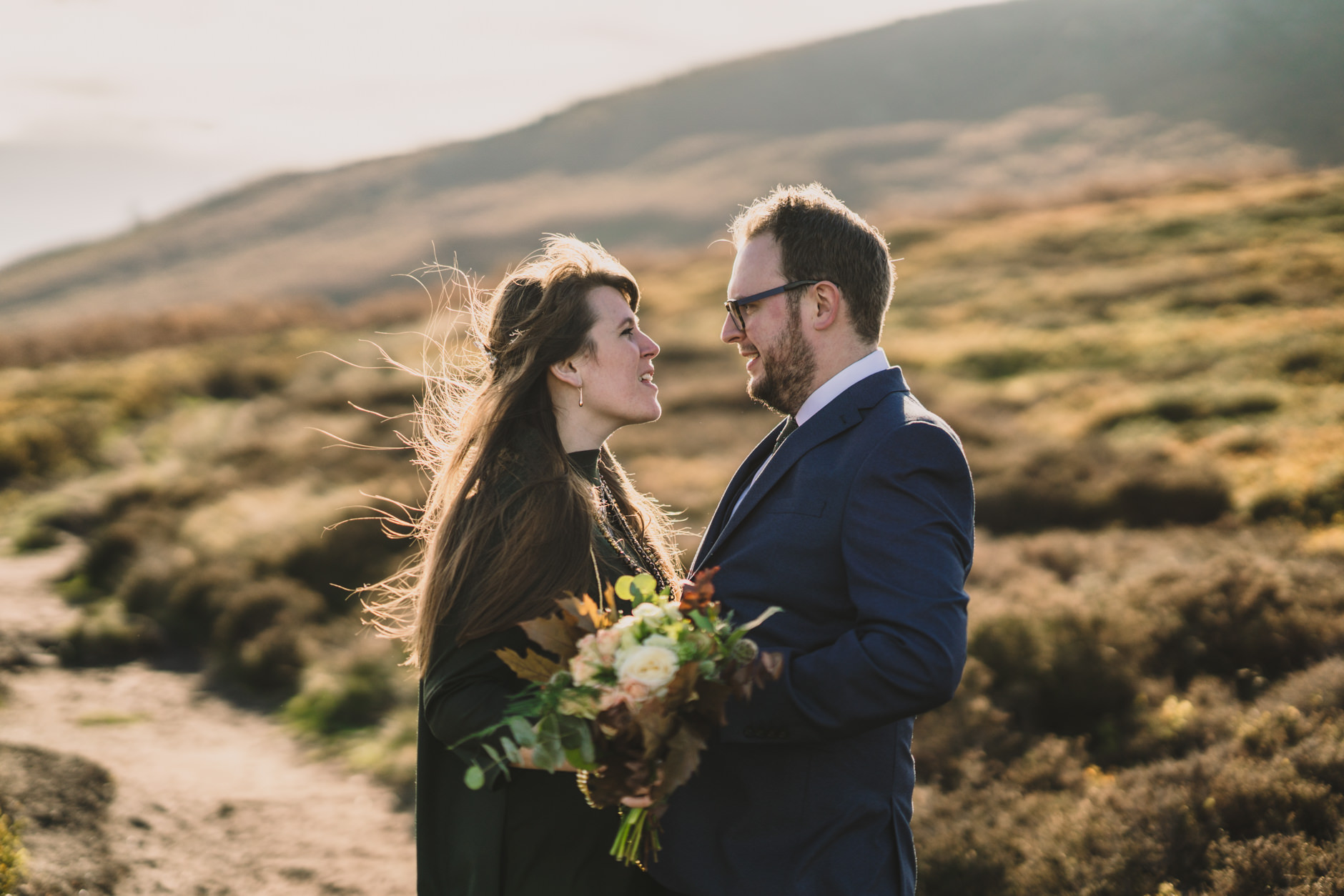bride in green shift dress with autumnal flowers and groom in blue suit